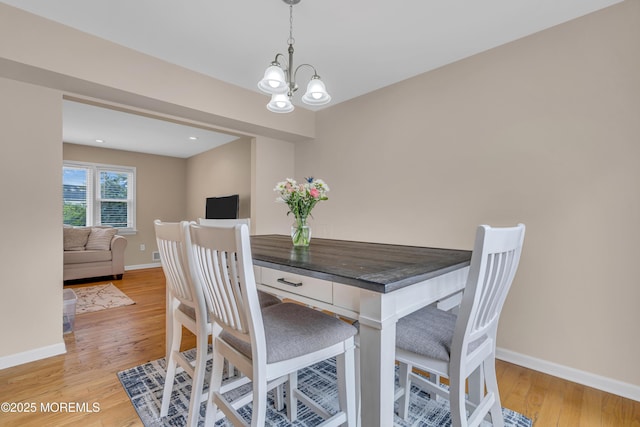 dining space featuring a chandelier, baseboards, and light wood-style flooring
