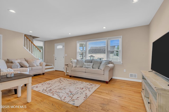 living area featuring stairway, baseboards, light wood-style floors, and recessed lighting