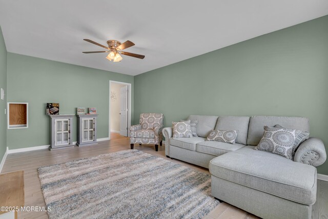 living area featuring a ceiling fan, baseboards, and wood finished floors