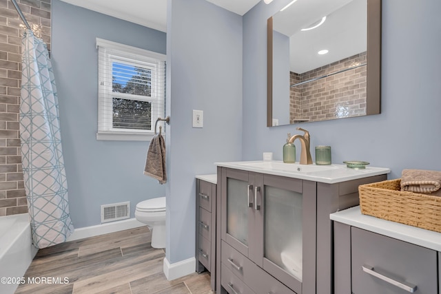 full bath featuring baseboards, toilet, wood finished floors, vanity, and shower / bath combo with shower curtain