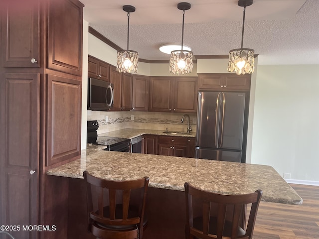1 Scenic Dr Unit 207, Highlands, NJ 07732 - kitchen with stainless steel appliances, a sink, a textured ceiling, wood finished floors, and decorative backsplash