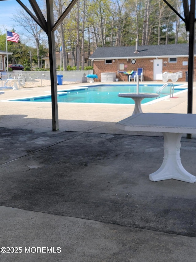 pool with an outbuilding, a patio, and fence