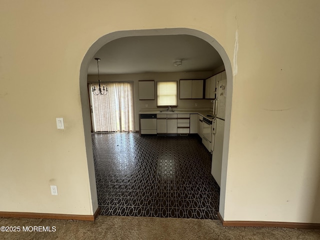 kitchen with white cabinets, an inviting chandelier, dishwashing machine, and arched walkways