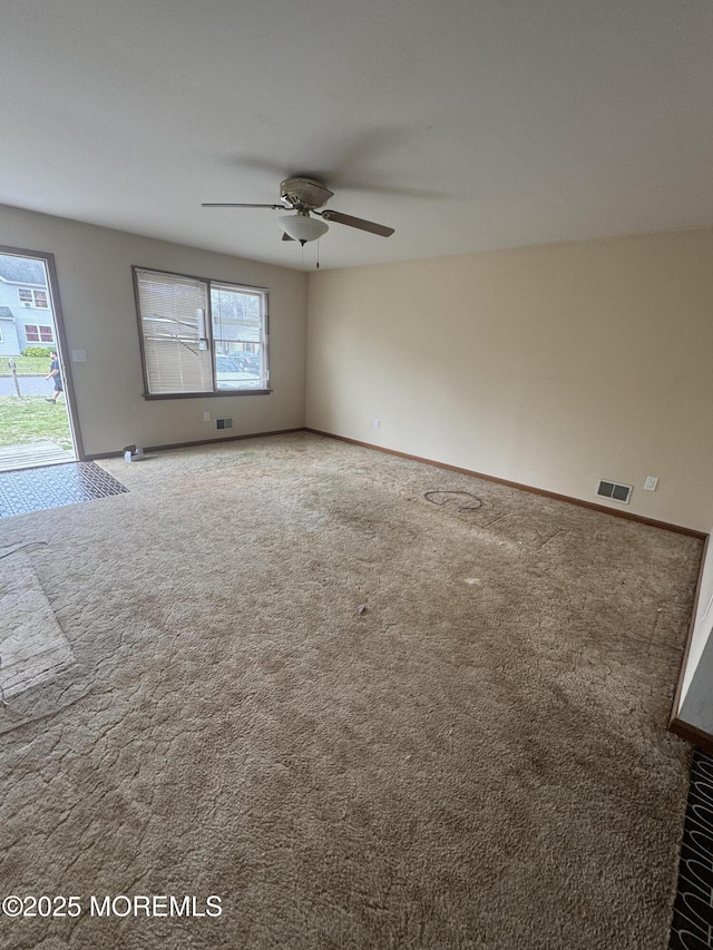 carpeted spare room with ceiling fan, baseboards, and visible vents