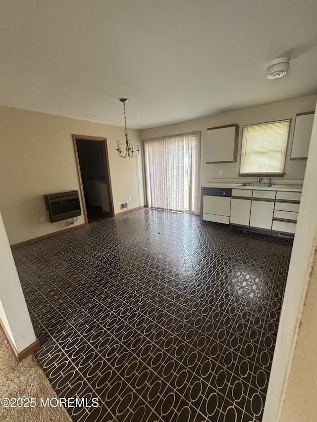 empty room with a sink, heating unit, a notable chandelier, and baseboards