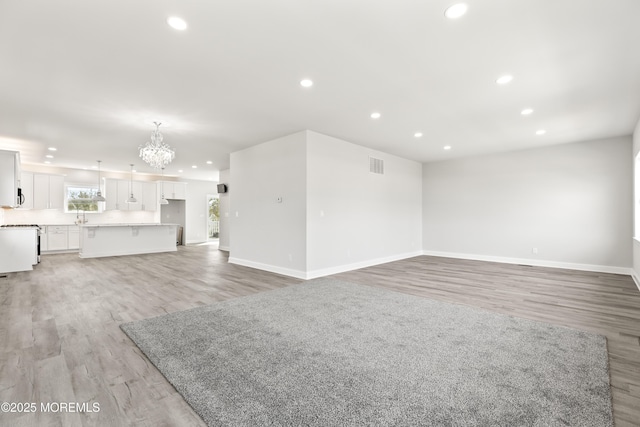 204 Morningside Ave, Union Beach, NJ 07735 - unfurnished living room with a chandelier, recessed lighting, light wood-type flooring, baseboards, and a sink