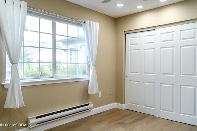 interior space featuring baseboards, light wood-style floors, baseboard heating, and recessed lighting