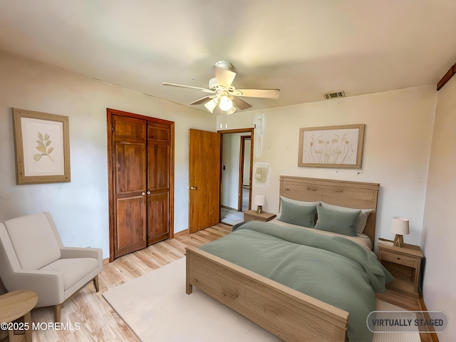 bedroom with light wood finished floors, a closet, ceiling fan, and visible vents