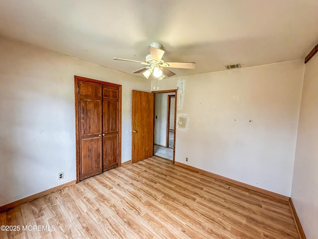 unfurnished bedroom featuring light wood finished floors, baseboards, a closet, and visible vents