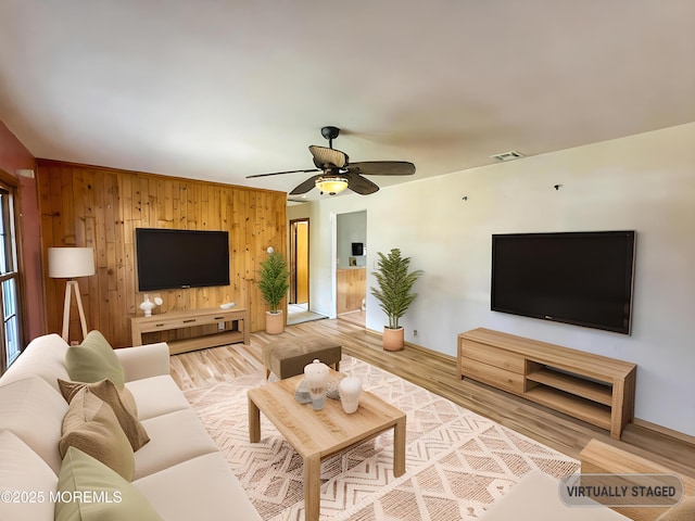 living area featuring baseboards, ceiling fan, visible vents, and wood finished floors