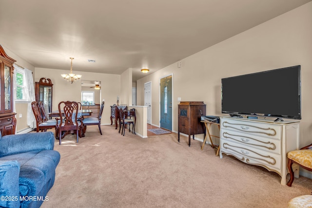 living room with a chandelier, light carpet, and baseboards