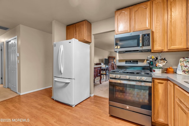 kitchen with appliances with stainless steel finishes, light wood-style flooring, light countertops, and baseboards