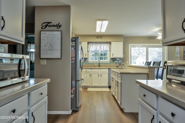 204 Stormy Rd, Manahawkin, NJ 08050 - kitchen featuring a sink, light wood finished floors, decorative backsplash, white cabinets, and appliances with stainless steel finishes