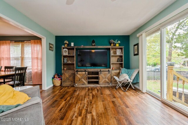 living room featuring wood-type flooring, plenty of natural light, and baseboards