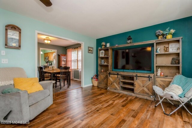 living area with wood finished floors, baseboards, and ceiling fan