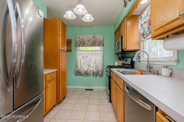 kitchen with stainless steel appliances, a sink, light countertops, and baseboards