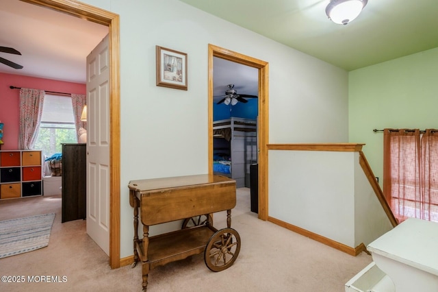 corridor featuring carpet floors, baseboards, and an upstairs landing