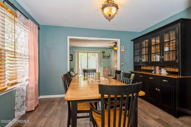 dining space with dark wood-style flooring, a ceiling fan, and baseboards