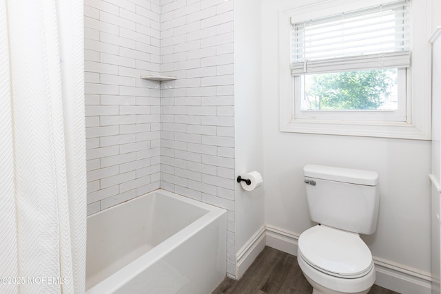 bathroom featuring toilet, wood finished floors, baseboards, and shower / tub combo with curtain