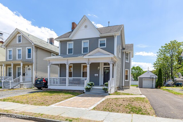 view of front facade featuring covered porch, a garage, an outbuilding, driveway, and a chimney