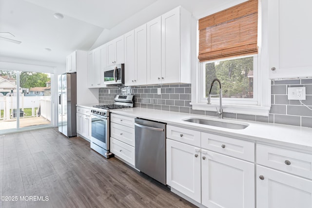 kitchen featuring appliances with stainless steel finishes, a sink, vaulted ceiling, light countertops, and white cabinetry