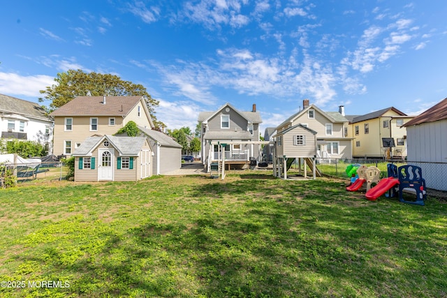 rear view of property featuring a playground, a residential view, and an outbuilding