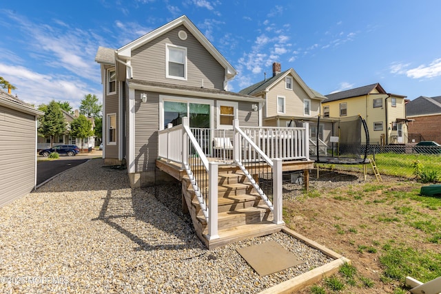 rear view of property featuring fence, a wooden deck, and a residential view