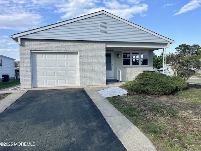 view of front facade with driveway, brick siding, central AC unit, and an attached garage