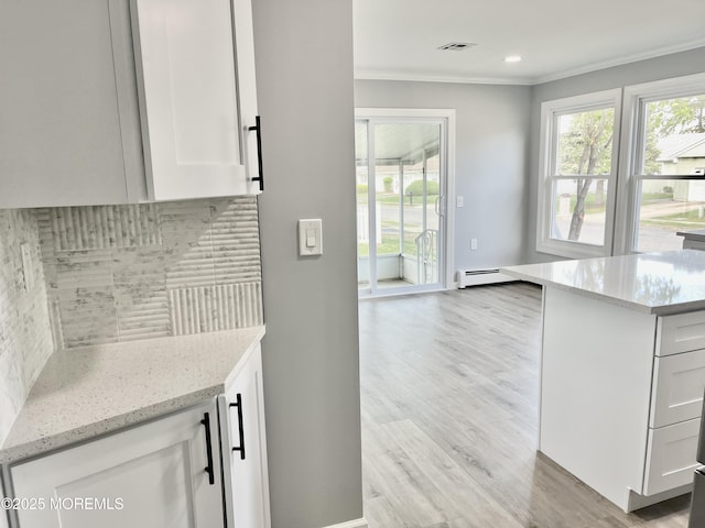 kitchen with light wood-style floors, white cabinets, tasteful backsplash, light stone counters, and crown molding