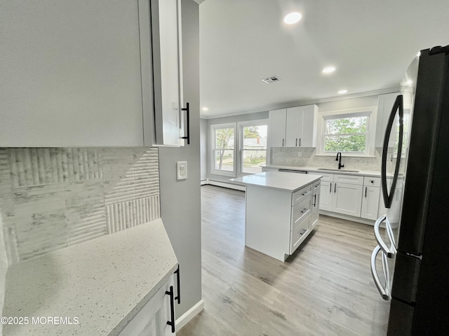kitchen featuring appliances with stainless steel finishes, a sink, backsplash, recessed lighting, and white cabinetry