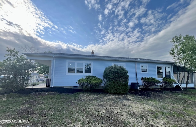 back of property with central AC, a chimney, and a lawn