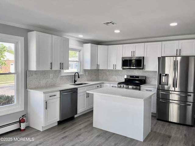 kitchen featuring appliances with stainless steel finishes, a sink, light countertops, crown molding, and backsplash