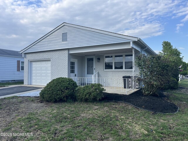 single story home with a garage, covered porch, brick siding, and asphalt driveway
