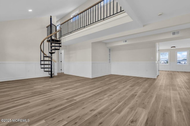 unfurnished living room with visible vents, wood finished floors, wainscoting, and stairs
