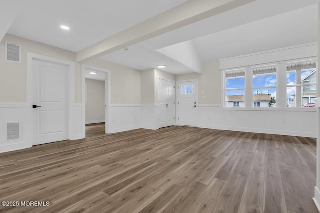 unfurnished living room with wainscoting, visible vents, and wood finished floors