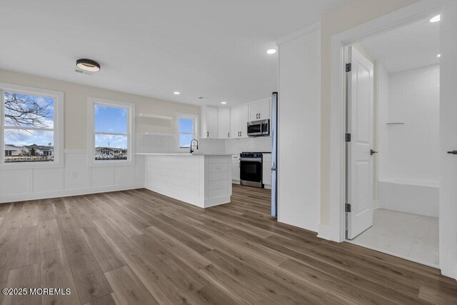 unfurnished living room with wainscoting, recessed lighting, and wood finished floors