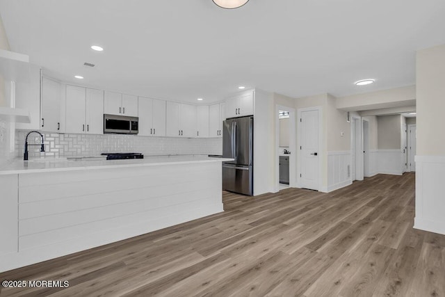 kitchen featuring light countertops, stainless steel appliances, a peninsula, and a sink