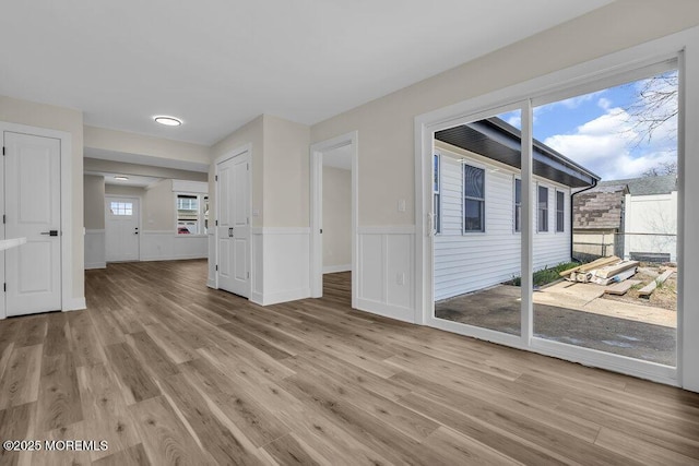 empty room with light wood finished floors and a wainscoted wall