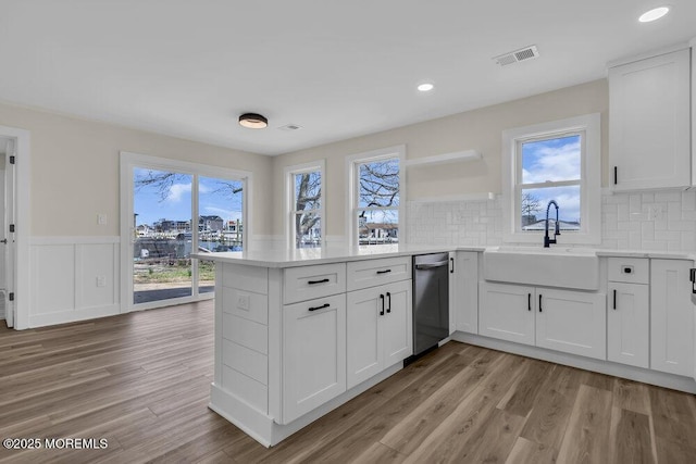 kitchen featuring dishwasher, visible vents, a sink, open shelves, and a peninsula