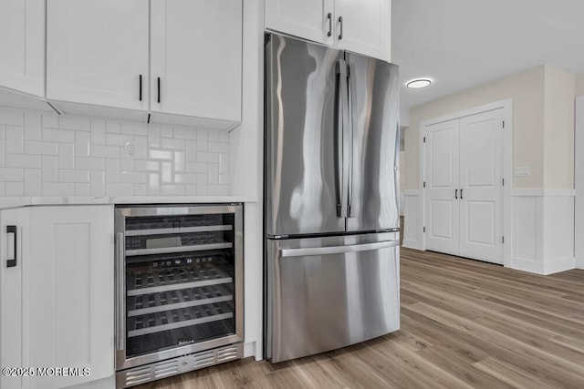 kitchen with beverage cooler, freestanding refrigerator, white cabinets, light countertops, and decorative backsplash