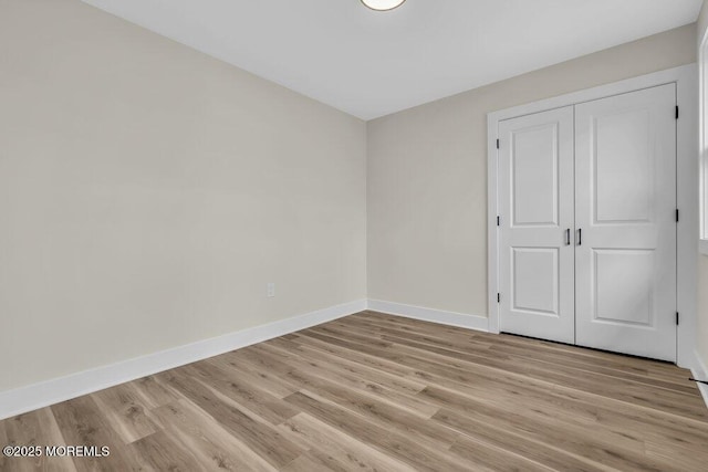 unfurnished bedroom featuring baseboards, a closet, and light wood-type flooring