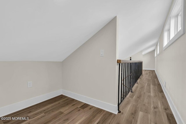 additional living space featuring baseboards, vaulted ceiling, and wood finished floors