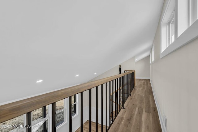 hall featuring an upstairs landing, wood finished floors, baseboards, and recessed lighting