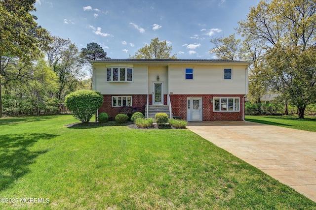 raised ranch featuring a front lawn, brick siding, and driveway