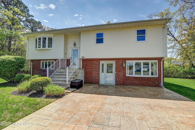 raised ranch featuring brick siding, a front yard, and a patio