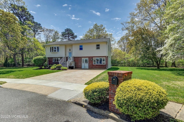 bi-level home with a front yard, brick siding, and driveway