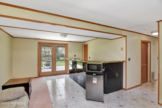 kitchen featuring light floors, visible vents, baseboards, ornamental molding, and black microwave