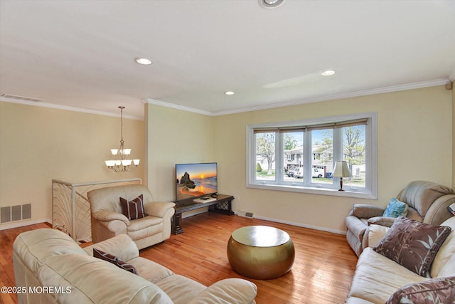 living room with a chandelier, wood finished floors, visible vents, and baseboards