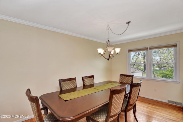 dining area with an inviting chandelier, crown molding, baseboards, and light wood-style floors