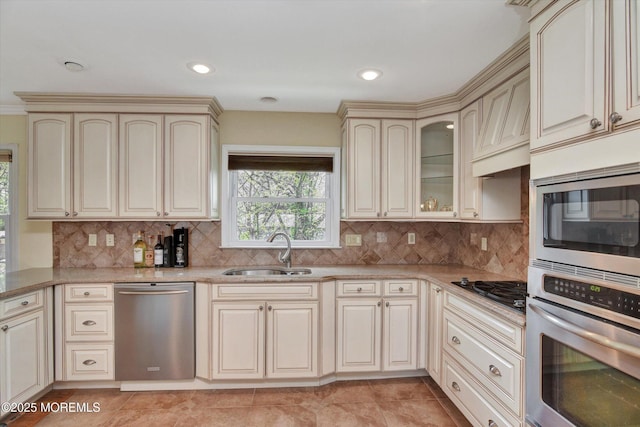 kitchen with a sink, stainless steel appliances, cream cabinetry, and decorative backsplash